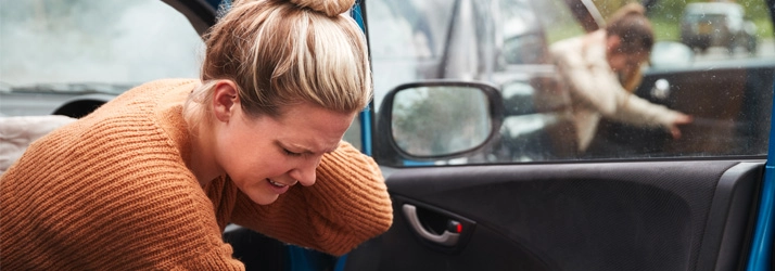 Two women holding their necks after a car accident.