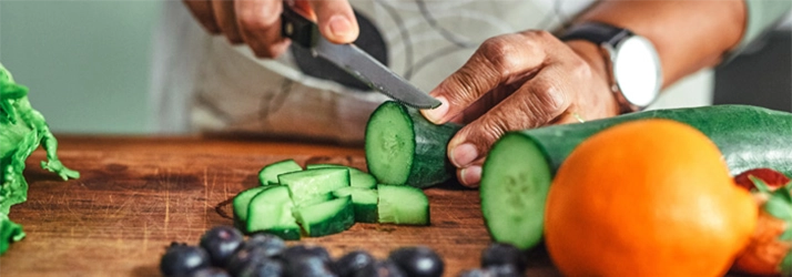 Chiropractic Gilbert AZ Man Cutting Food A person cutting fresh vegetables on a wooden cutting board.