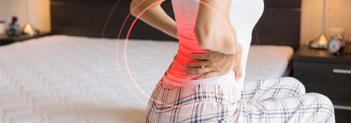 Chiropractic Gilbert AZ Woman With Lower Back Pain Woman on bed mattress with back pain.