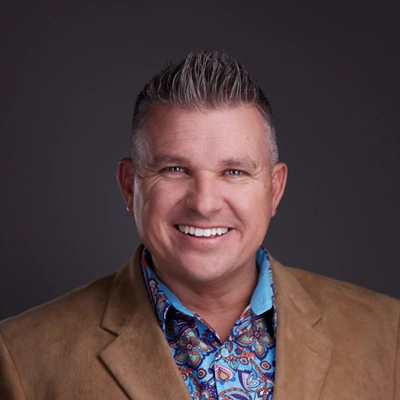 Dr. David Campbell smiling in a tan suit.