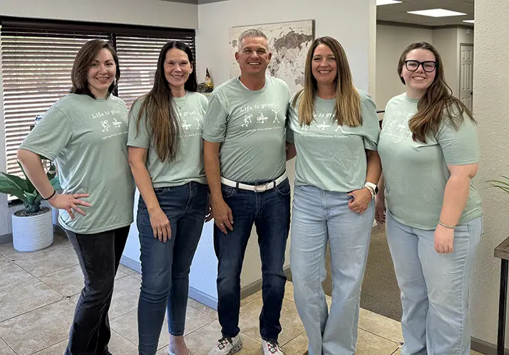 Chiropractor Gilbert AZ David Campbell With Wife And Team Dr. David Campbell smiling with his wife and team.